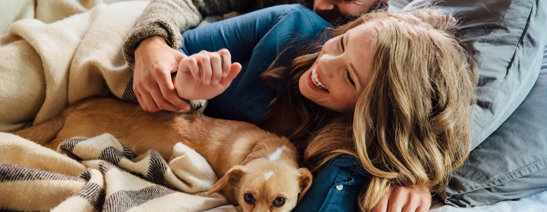 a man and woman lying in bed with a dog