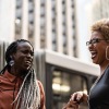 two women laughing in front of a building